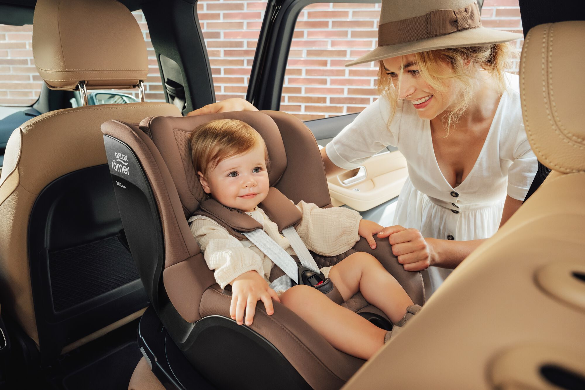 Taapero kiinnitettynä DUALFIX 5Z toddler car seat -turvaistuimeen, hänen äitinsä seisoo vieressä.